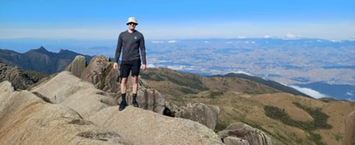 Teammitglied auf einem Berggipfel mit weitem Talblick